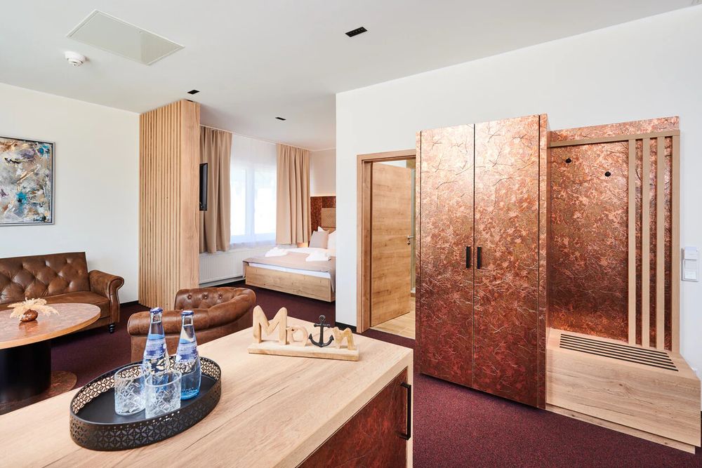 Wohnbereich der Familiensuite mit Ledersesseln, Esstisch und Blick ins Schlafzimmer