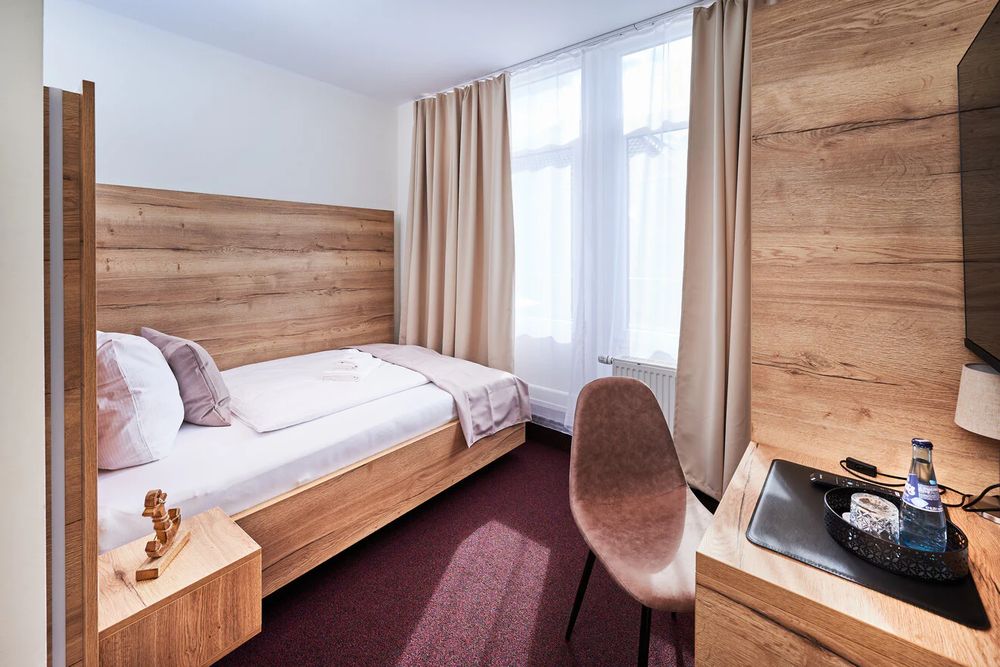 Einzelzimmer mit Schreibplatz und Holzmöbeln
