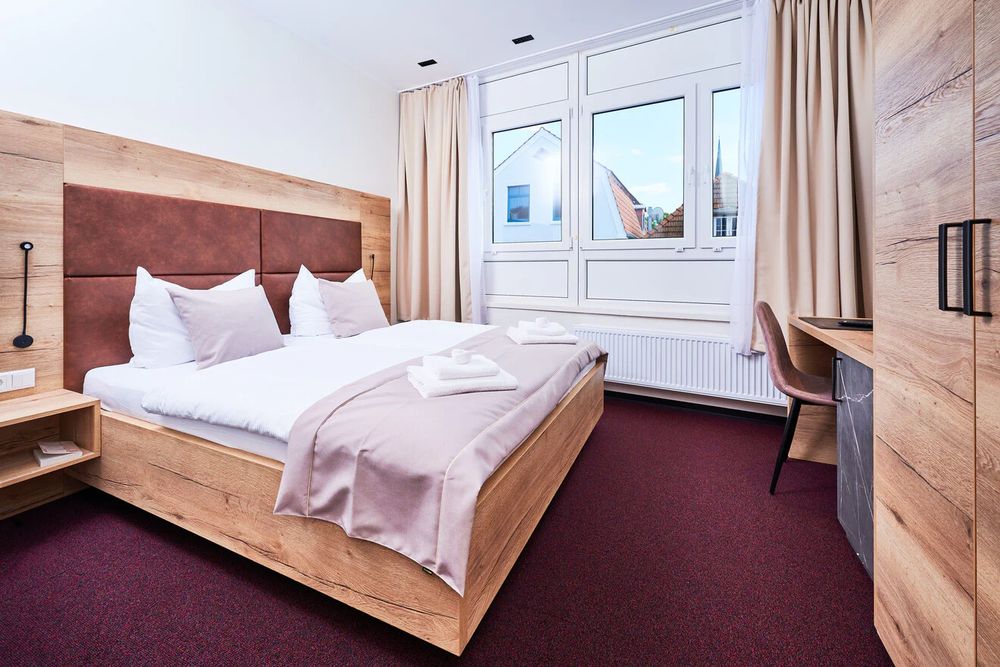Doppelzimmer im Hotel 53° Nord mit Holzbett, Lederkopfteil und Fenster zur Stadt
